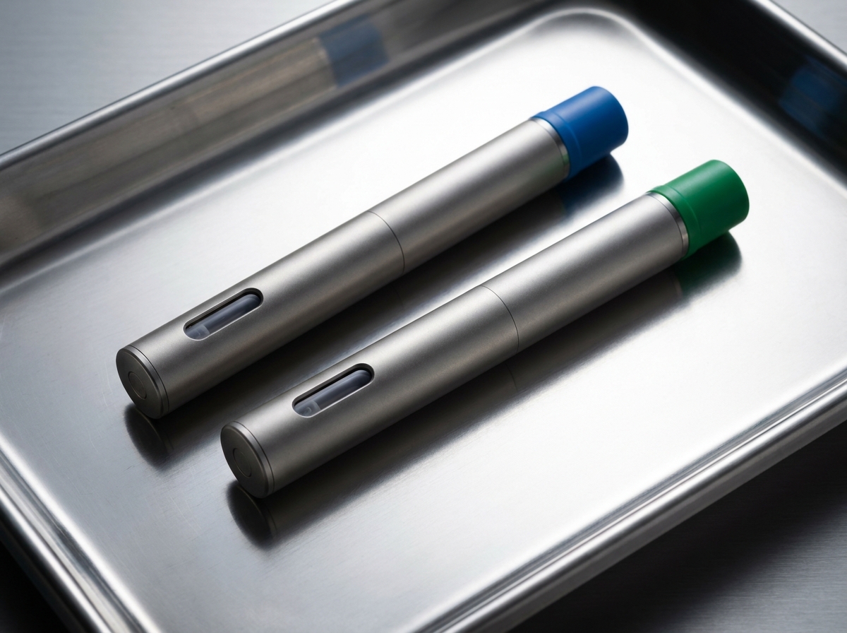 Two clinical injectable pen devices on a sterile stainless steel surface, one labeled with a blue cap and one with a…